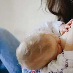 Mamma allatta il suo bambino, dimostrando che si può allattare con la febbre. Un momento di amore e cura.