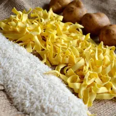 Reis, Nudeln und Kartoffeln liegen auf Jute. Was hat mehr Kalorien, Reis oder Kartoffeln? Die Antwort ist nicht so einfach.