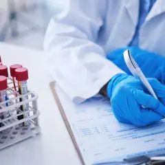 Rękawiczki, probówki z krwią i formularz medyczny. Wyniki badań wskazują na podwyższone leukocyty.