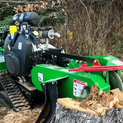 Grön stubbfräs med larvfötter redo att ta bort en stubbe i skogen.