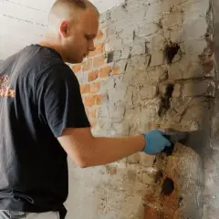Mann trägt Mörtel auf Ziegelwand auf, um sie gegen Wasser abzudichten.