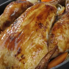 Un poulet rôti doré et juteux, accompagné de carottes et d'oignons. Un délice pour savoir quel vin avec un poulet rôti.