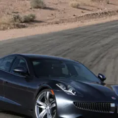 Elegancki, ciemny Fisker Karma na torze wyścigowym, gotowy do jazdy po pustynnych zakrętach.