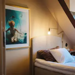 En konstnärlig tavla med en kvinna i en bur under vatten pryder väggen i ett mysigt rum på hotellet Höganäs.
