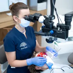 Doświadczony technik dentystyczny pracuje pod mikroskopem, dbając o każdy szczegół leczenia.