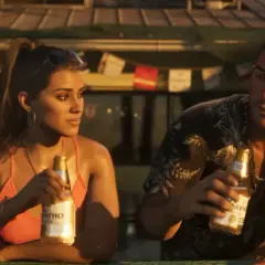 Lucia z GTA 6 i jej partner relaksują się z piwem w słoneczny dzień.