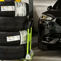 Cztery nowe opony Michelin CrossClimate 2, uznawane za najlepsze opony wielosezonowe, czekają na montaż w czarnym aucie.