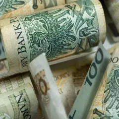 Zwijane banknoty 100 zł, czyli kosiniakowe, tworzą stos. Widoczny orzeł i napis Narodowy Bank Polski.
