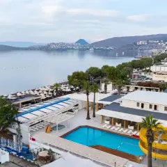 Widok na basen i plażę z leżakami. W tle morze i zabudowania. Idealne miejsce na wakacje, jak sugerują petunya beach resort opinie.