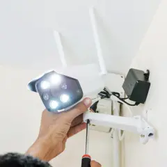 Montaż kamery, która działa tylko na wifi. Ręka przykręca śrubę mocującą urządzenie do ściany.