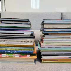 Dwie wysokie sterty książek na kanapie. Zastanawiasz się, co zrobić ze starymi książkami? Może czas na porządki i nowe historie?