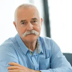 Portret starszego mężczyzny z siwymi włosami i wąsami, w niebieskiej koszuli.