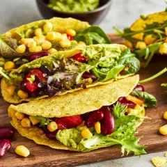 Knusprige, vegetarische Tacos gefüllt mit Guacamole, Kidneybohnen, Mais, Tomaten und Salat. Ein bunter Genuss!