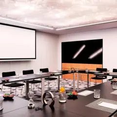 Nowoczesna sala konferencyjna w Renaissance Hotels Warszawa. Stoły, projektor, ekran i stylowe detale tworzą idealne miejsce na spotkania.