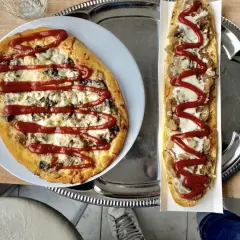 Polska pizza i zapiekanka z serem, grzybami i keczupem na tacy.