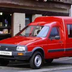 Czerwony Citroen C15, dostawczy klasyk, parkuje przed sklepem z pamiątkami.