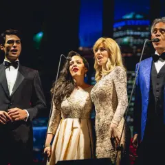 Andrea Bocelli śpiewa z synem i dwiema artystkami na scenie.