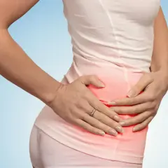 Kobieta trzyma się za prawy bok, gdzie widoczny jest czerwony obszar bólu.