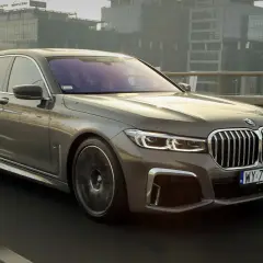 Eleganckie BMW 745Le w kolorze grafitowym sunie po moście, mijając nowoczesne budynki.