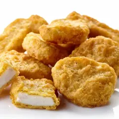 Złociste nuggetsy z kurczaka, jeden przekrojony, ukazujący białe mięso. Ile kcal ma 6 mcnuggets?