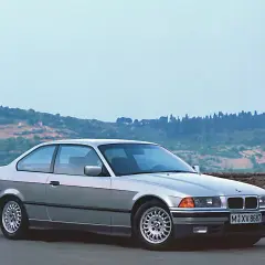 Srebrne BMW E36 coupe, idealne auto do driftu, stoi na tle malowniczego krajobrazu Toskanii.