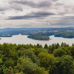 Widok na Jezioro Solińskie zalesione wzgórza i chmury. Solina atrakcje to raj dla miłośników przyrody i spokoju.