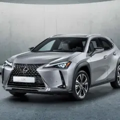 Srebrny Lexus UX 250h stoi na tle betonowej ściany. Elegancki crossover miejski gotowy na przygodę.