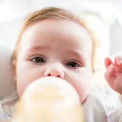 Urocze niemowlę pije mleko z butelki. Ważne jest, jaka temperatura mleka dla noworodka, by było bezpieczne i komfortowe.