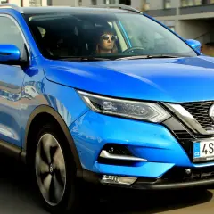 Niebieski Nissan Qashqai w ruchu. Kierowca w okularach przeciwsłonecznych. Sprawdź nissan qashqai wymiary.