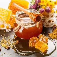 En burk gyllene honung, honungskaka och bipollen. Honung nyttigt för hälsan, omgiven av blommor.