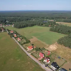 Widok z lotu ptaka na wieś otoczoną lasem. Domy z czerwonymi dachami, pola i jezioro. Zastanawiasz się, ile to ar?