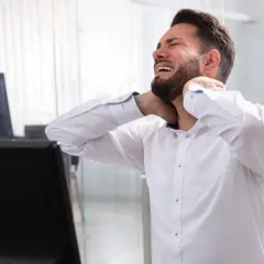 Mężczyzna z bólem karku, szukający leków na sztywność karku.