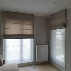 Eleganckie rolety rzymskie i zasłony tworzą przytulną atmosferę w pokoju.