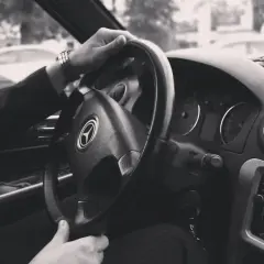 Dłoń na kierownicy samochodu, widok z wnętrza pojazdu.