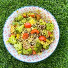 Ensalada de pasta con brócoli, tomates cherry y semillas. Los ingredientes frescos y coloridos la hacen irresistible.