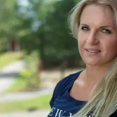 Frida, en stark frida boxare, ler mot kameran. Bakom henne syns en grönskande sommaridyll.