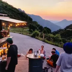 Gente disfrutando de comida y bebida en un food truck con vistas a montañas al atardecer. Un lugar ideal para descubrir los mejores pueblos para comer en Asturias.