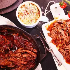 Saftigt pulled beef i en gjutjärnsgryta, serverat med krämig coleslaw och färska tomater. Perfekt för en mysig middag.