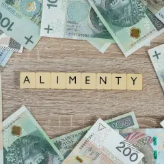 Litery "ALIMENTY" na tle polskich banknotów. Pytanie: ile wynoszą alimenty z funduszu alimentacyjnego?
