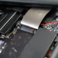 Nahaufnahme eines Motherboards, bereit für die m2 ssd installieren. Ein silbernes Kabel ist mit einem Anschluss verbunden.
