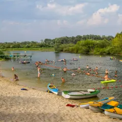 Wola Uhruska tętni życiem. Ludzie kąpią się, pływają na łódkach i relaksują na piaszczystej plaży.
