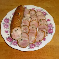 Kiełbasa drwala przepis: pokrojona w plastry, aromatyczna kiełbasa na talerzu z kwiatowym wzorem. Idealna na grilla lub jako dodatek do dania.