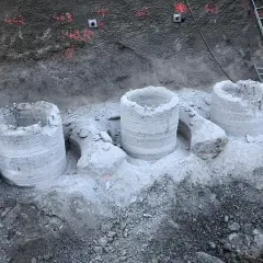 Bohrpfähle ragen aus dem Erdreich, die Reste einer tangierenden bohrpfahlwand. Eine Leiter lehnt an der Wand.