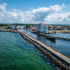 Port w Darłowie z falochronem, statkiem pirackim i nowoczesnym budynkiem. Atrakcje turystyczne na wyciągnięcie ręki.
