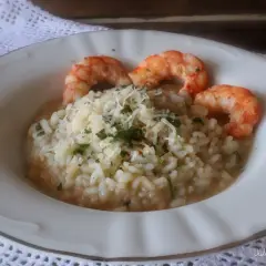 Delicioso risotto de langostinos cremoso, coronado con queso rallado y perejil fresco. Un plato principal que invita a disfrutar.