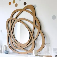 Miroir en bois au design entrelacé, parfait pour une diy deco murale. Des points colorés décorent le mur blanc.