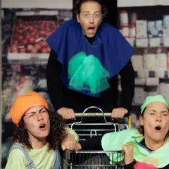 Drei Schauspieler im **Horizont Theater** mit Einkaufswagen, die mit übertriebenen Gesichtsausdrücken singen.