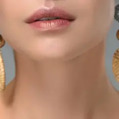 Labios maquillados y pendientes dorados con detalles que recuerdan a tipos de piedras preciosas.