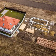 Budowa domu na działce 3 klasy ziemi. Fundamenty, drewno i cegły czekają na realizację warunków zabudowy.