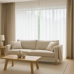 Sofá beige, mesa de centro de madera y cortinas de lino, un ejemplo de las últimas tendencias en cortinas para salón.